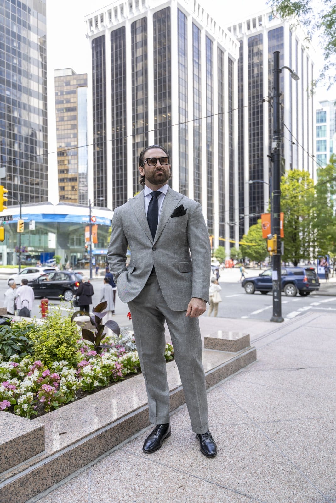 Man wearing a grey suit on a downtown Vancouver sidewalk.